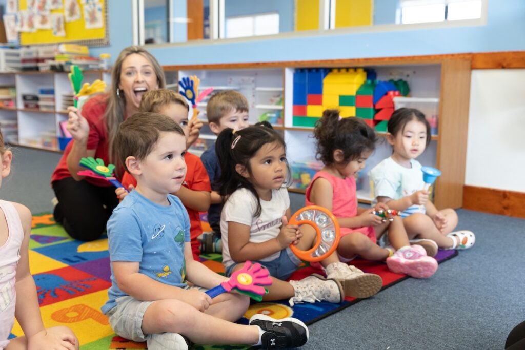 A group of kids play musical instruments in an Ivy KIds classroom.